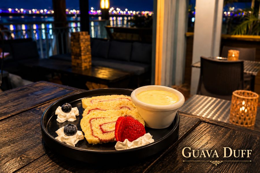 Guava duff slices with warm sauce and whipped cream at night